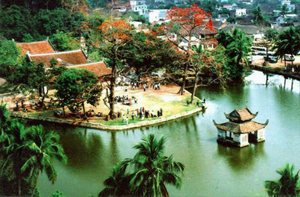 Nhìn từ trên cao một quần thể chùa bên hồ nước, có gác thuỷ đình nổi giữa hồ và cây hoa phượng đỏ