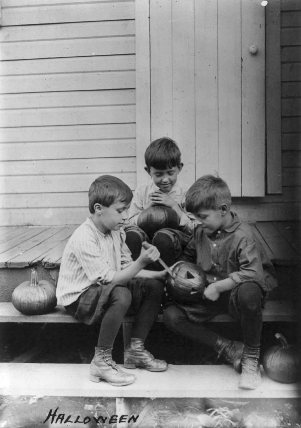 Ảnh đen trắng năm 1917: ba cậu bé ngồi trên hiên nhà gỗ khoét bí ngô làm đèn Halloween