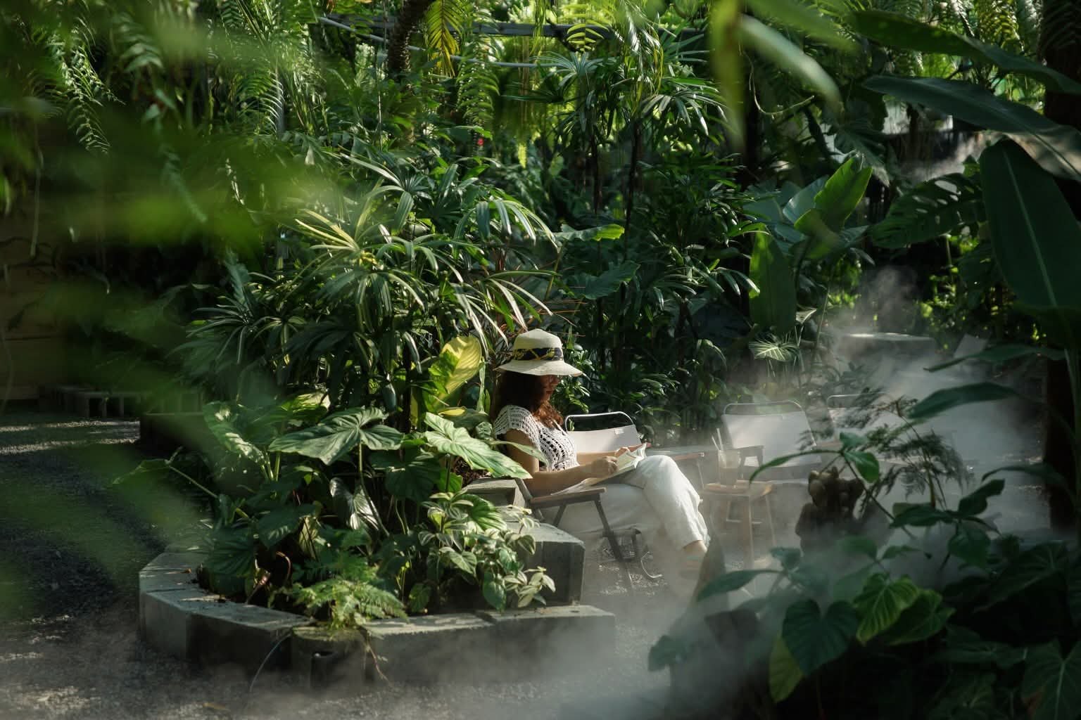 Góc đọc sách giữa vườn văn phòng Silver Cloud, sương phun lan trên lối sỏi, bồn block trồng philodendron xung quanh