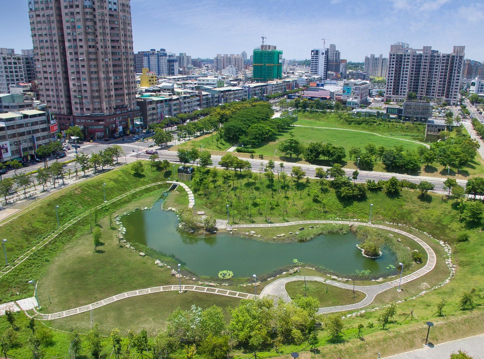 Ảnh từ trên cao một hồ điều hoà hình cong lớn nằm giữa công viên cây xanh, chung cư cao tầng xung quanh