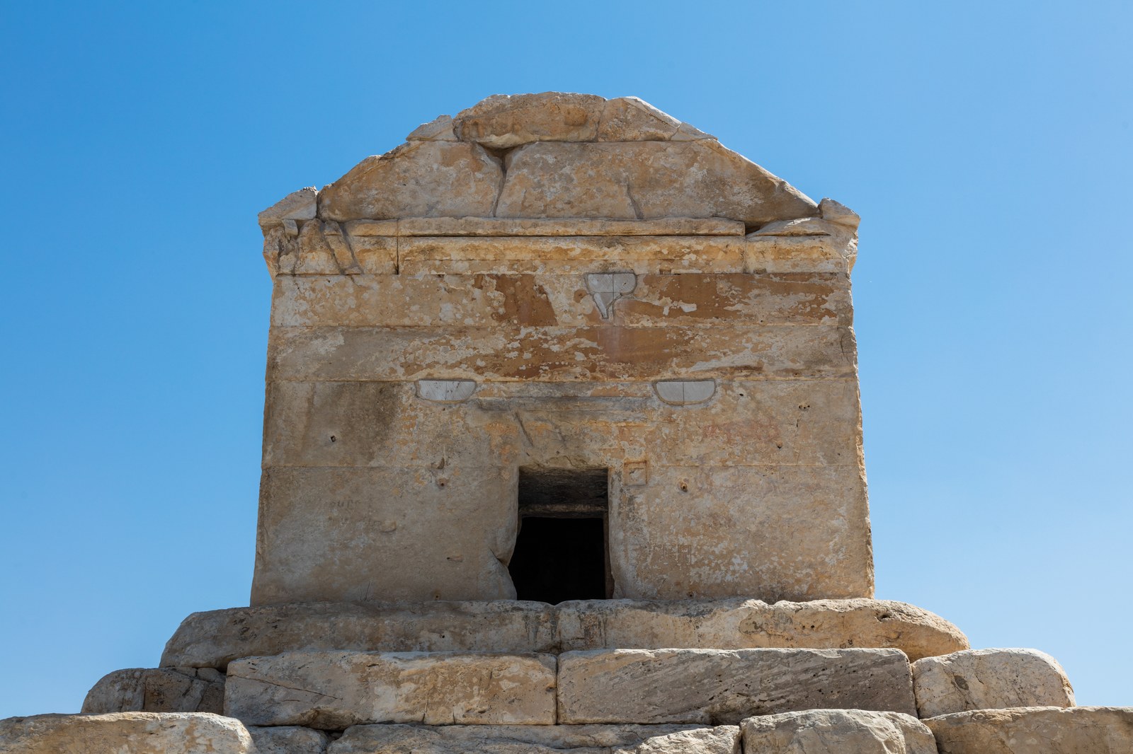 Lăng mộ hình khối chữ nhật mái dốc của Cyrus Đại đế tại Pasargadae, xây bằng đá vôi trên nền bậc thang, nổi bật trên nền trời xanh