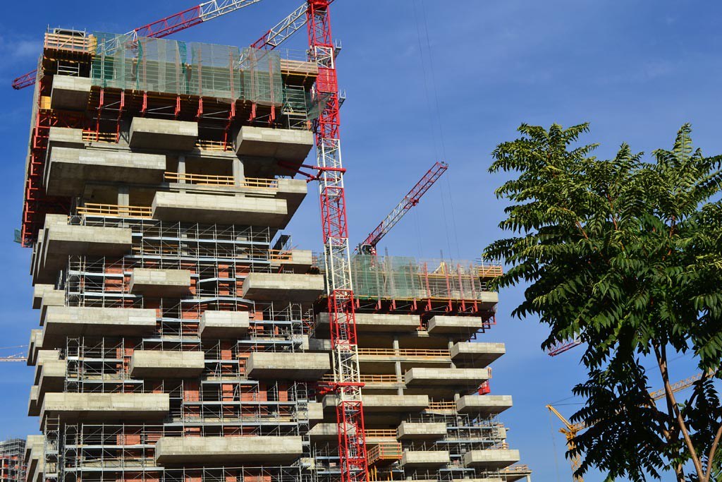 Công trường xây dựng Bosco Verticale với cần cẩu tháp, các tầng bê tông có bậc lùi để sau này đặt chậu cây lớn