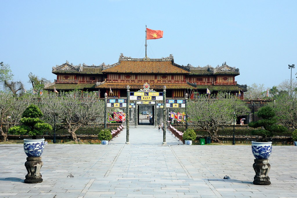 Một cổng thành trong Kinh thành Huế nhìn thẳng, có quốc kỳ trên nóc, hai trụ đá cùng bình gốm men lam hai bên lối vào